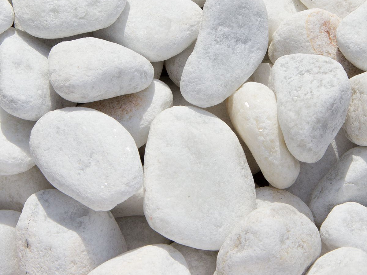 A close-up view of numerous smooth, white Brisks 20-40mm White Pebbles and stones, varying in size and shape, lying closely together. Perfect for landscaping projects, these small white stones have a uniform texture with subtle shades of grey and some slight imperfections.