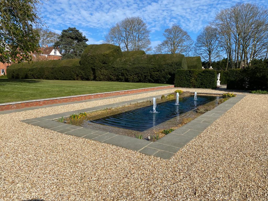 a small pond in the middle of a graveled area