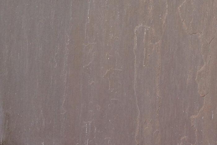 A close-up view of an Autumn Brown Sandstone Paving Slabs surface by Brisks, predominantly in shades of brown and gray. The sandstone paving slabs display natural vertical striations and subtle color variations, creating an intricate and earthy pattern with beautiful natural tones.