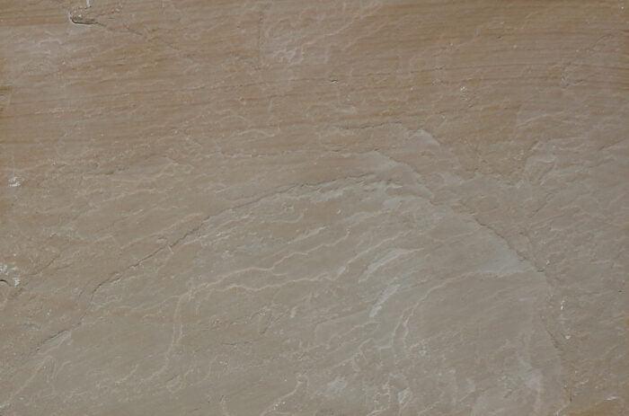 Close-up of the Brisks Buff Sandstone Paving Slabs surface showcasing a mix of tan and light brown hues, with gentle vein patterns that contribute to a natural and earthy aesthetic.