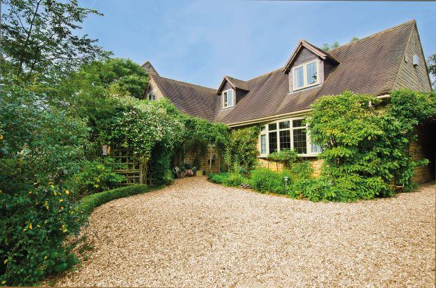 a house with a gravel driveway surrounded by trees