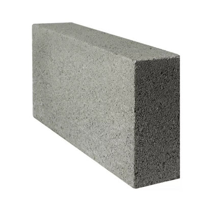 A gray, rectangular Brisks 100mm Solid Dense 7.3N Block with a rough texture is slightly tilted to the left against a white background. Its top, side, and front surfaces are visible, highlighting its reliable strength—a cost-effective choice for construction projects.