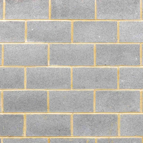 A close-up of Brisks' 100mm Solid Dense 7.3N Blocks shows a gray brick wall with a grid pattern and rows of rectangular bricks. Known for their reliable strength, these blocks offer a smooth, uniform texture and are a cost-effective choice for construction projects.