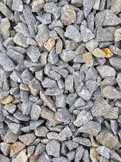 A close-up of Brisks' 20mm Cornish Granite showcases small, irregularly shaped chippings with specks of brown and orange. These driveway stones feature a rough texture and are tightly packed together, making them ideal for enhancing your landscaping projects.