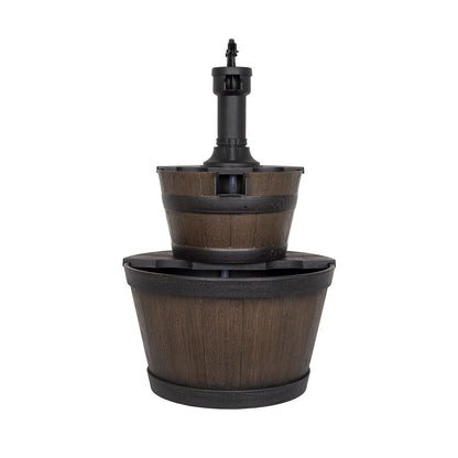 This self-contained outdoor water feature from La Hacienda, named Whiskey Bowls, is a two-tiered wooden barrel fountain with a black center spout. The lower barrel supports the slightly smaller upper one, both boasting a dark wood finish and black trim reminiscent of classic designs.