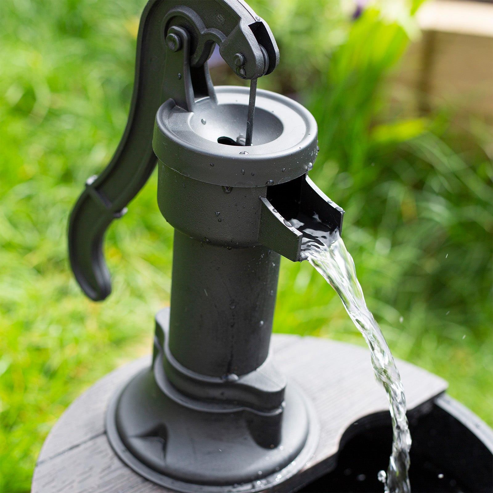 A close-up of the La Hacienda Whiskey Bowls with water flowing gently, reminiscent of a self-contained fountain. Set against a blurred green garden background, this outdoor water feature creates an elegant focal point.