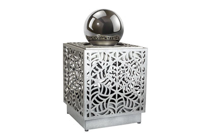 The La Hacienda Rene Cascade Water Feature by La Hacienda is a decorative metallic cube featuring intricate cut-out patterns on all sides, perfect for your outdoor space. Atop the cube rests a reflective, shiny metallic sphere. Its modern and artistic design is further enhanced by an integrated water feature with a subtle recirculating pump.