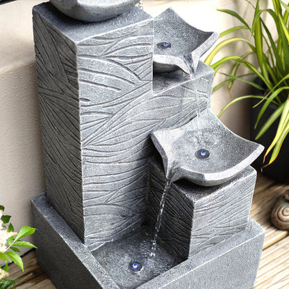 La Hacienda introduces the Jackson Pours incl LEDs, a contemporary tabletop water fountain with a stone-like texture and three cascading tiers. Gentle streams of water elegantly descend, making it a perfect complement to garden water features amidst lush greenery and wooden surfaces.