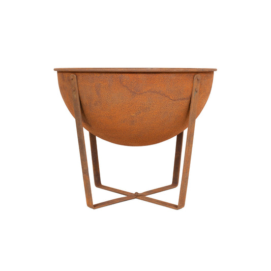 The La Hacienda Tamba Small Firepit from La Hacienda features a rusted, oxidized surface that highlights its cast iron and steel construction. It is designed in a bowl shape and rests on a simple metal stand with crossed supports, beautifully complementing its deep, round basin with a weathered texture.