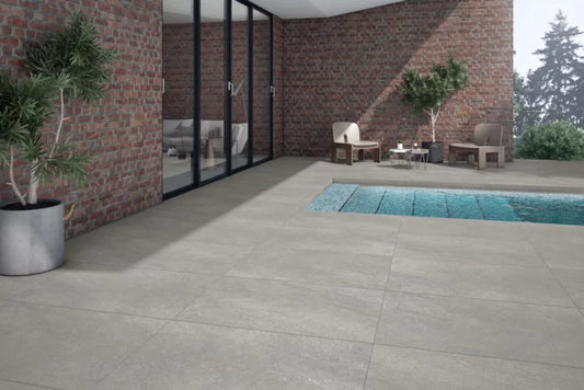A close-up of a textured surface featuring a blend of light beige and gray tones, resembling stone or concrete. Similar to Brisks' Ancient Grey Porcelain Paving, the pattern is uneven with subtle variations in color and texture—ideal for contemporary design needs.