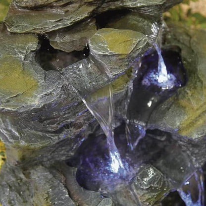 The La Hacienda Como Springs (Inc. LED) Water Feature by La Hacienda is a cascading tabletop fountain with three levels of stone-like textures. Water gently flows from the top tier to the middle and into the base, all illuminated by soft blue LED lights, creating a tranquil and soothing effect. Its durable resin structure enhances both longevity and charm.