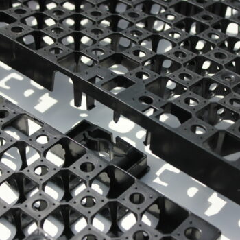 The CORE DRAINBASE by Core LP (pack of 60) is a textured black HDPE plastic grid with geometric holes and intersecting lines. Perfect for roof garden drainage, it creates striking reflections on reflective surfaces.