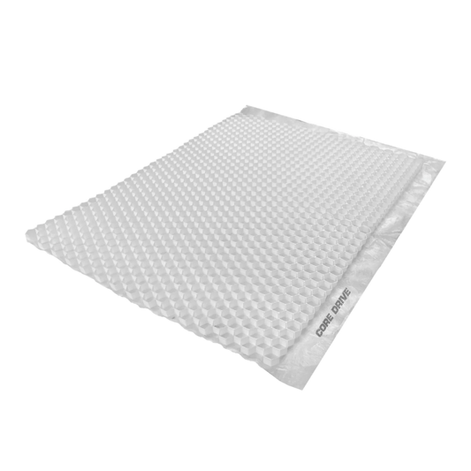 A light gray, rectangular bubble mailer with a textured surface is seen at an angle, reminiscent of porous geotextile. A strip on the side is labeled "CORE DRIVE 40-30 / 40-40 - Gravel Grid" from Core LP.