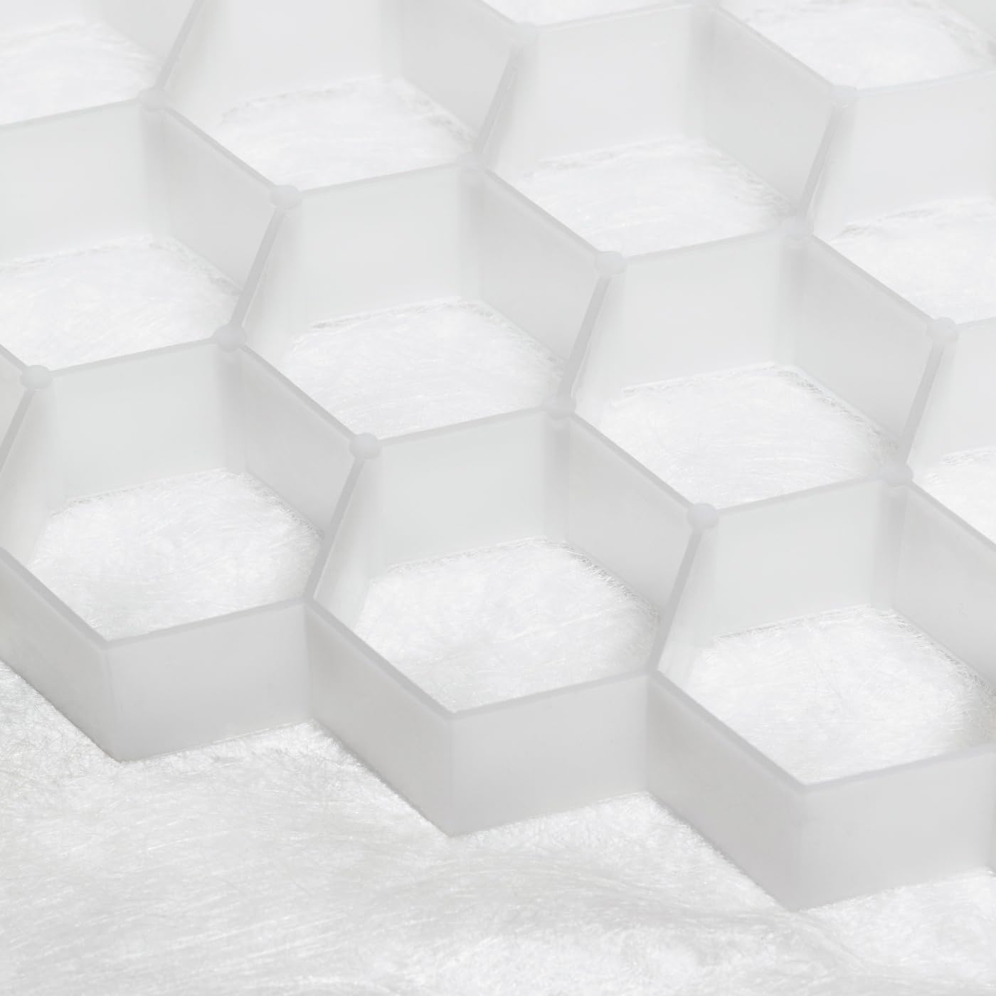 The CORE PATH PRO 45-20 by Core LP features a translucent hexagonal grid pattern on a soft white surface, evoking a honeycomb. This minimalist design showcases the innovation utilized in gravel grid systems for Sustainable Drainage Systems (SuDS).