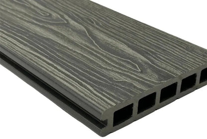 Close-up of Deck&Grass's Woodgrain Composite Decking Board in dark gray, perfect for outdoor spaces. It showcases a wood grain texture and hollow rectangular sides, with one edge focused to emphasize its layered, low-maintenance design.