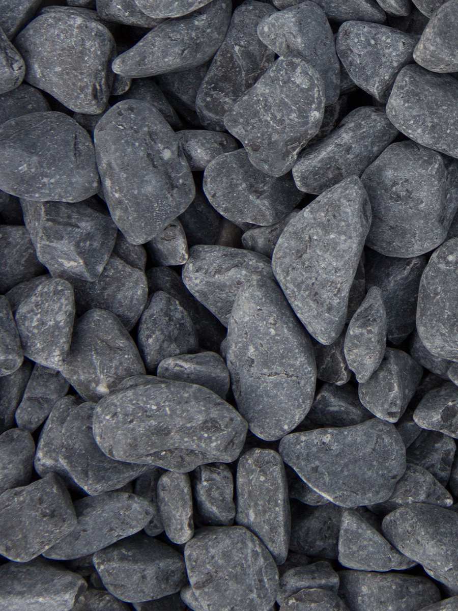 A close-up of Brisks Ebony Black Pebbles reveals a pile of smooth, dark gray stones for landscaping and decoration. These closely packed, matte-textured pebbles vary in size and shape, with surfaces that appear slightly rugged and natural.