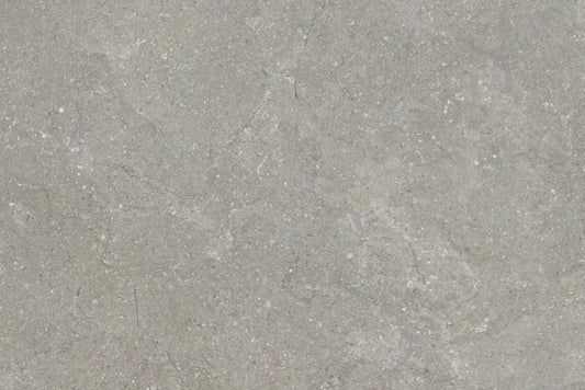 A close-up view of Brisks' Next Grigio Porcelain Paving shows its textured gray stone surface, featuring subtle tone variations and faint white speckles that exude urban elegance. It's ideal for outdoor entertainment areas with a natural, rugged appearance.