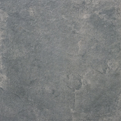 A close-up of the Priorat Graphite Porcelain Paving by Brisks showcases a textured stone-like surface, with shades of gray and subtle hints of blue and white. The natural cracks and variations evoke a rugged beauty, ideal for slip-resistant applications.