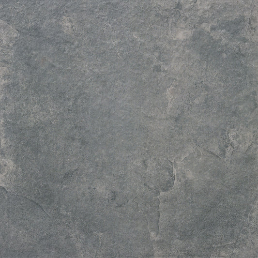 A close-up of the Priorat Graphite Porcelain Paving by Brisks showcases a textured stone-like surface, with shades of gray and subtle hints of blue and white. The natural cracks and variations evoke a rugged beauty, ideal for slip-resistant applications.