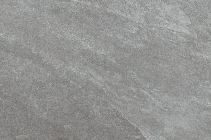 A close-up of a gray, textured stone surface with subtle variations in shade and rough, natural patterns, reminiscent of Brisks' Rasa Grigio Porcelain Paving tiles known for their premium durability.