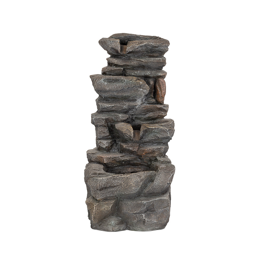 Introducing the "Hamsterley Springs incl LEDs" by La Hacienda: a tall and beautifully crafted stone water fountain featuring multiple tiers. Its dark gray stones are meticulously arranged to mimic a natural rock formation, delivering a cascading water effect driven by a solar-powered pump. This robust water feature boasts an earthy appearance and includes LED lighting to enhance its allure.