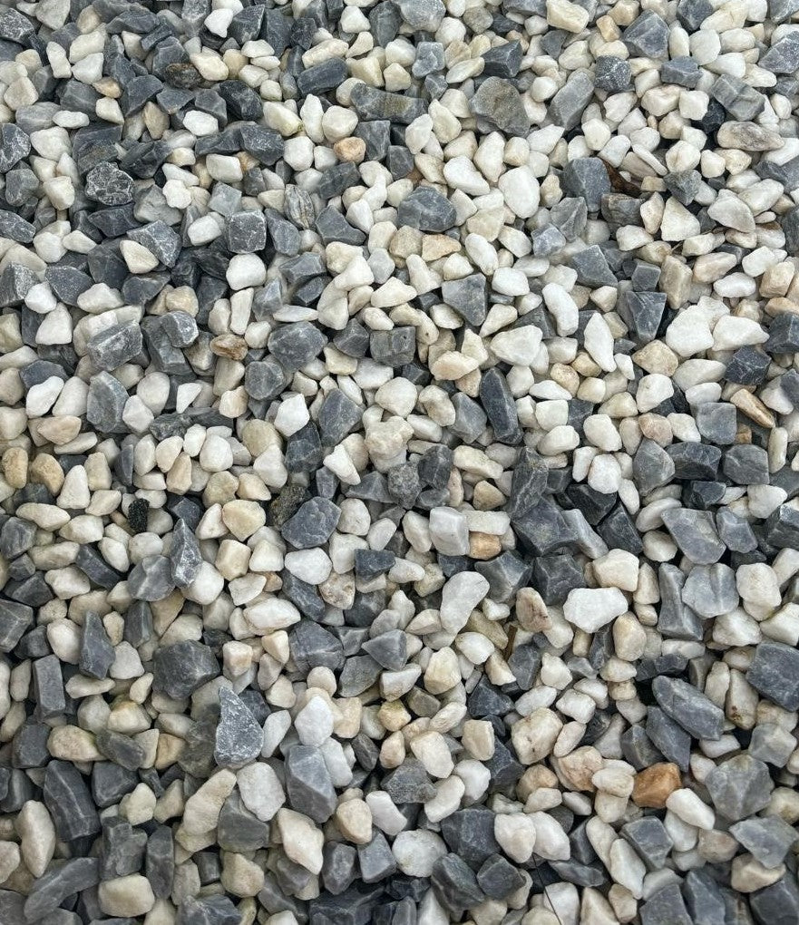A close-up of small Brisks 10-20mm Arctic Blue Chippings in varying shades of grey, white, and subtle hints of blue. The irregularly shaped stones are densely packed together, creating a textured surface.
