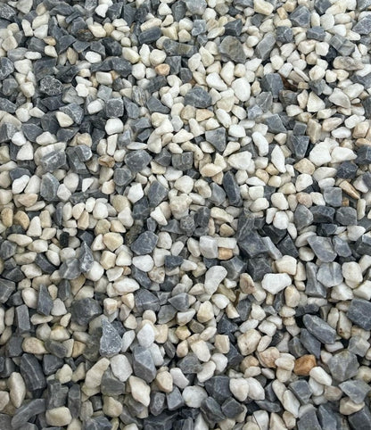 A close-up of small Brisks 10-20mm Arctic Blue Chippings in varying shades of grey, white, and subtle hints of blue. The irregularly shaped stones are densely packed together, creating a textured surface.