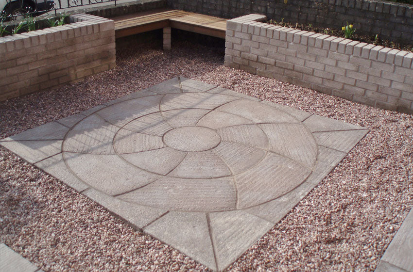 A stone square in gravel with brick walls, crafted using Brisks' Weathered Slate Catherine Wheel Kit by Bowland Stone for a timeless look.