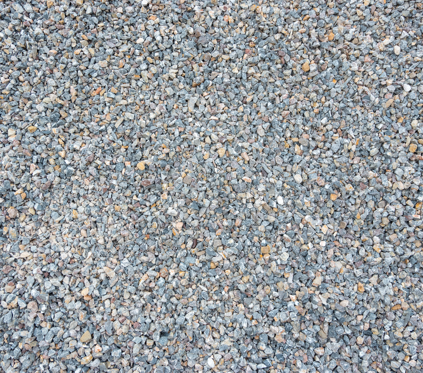 A close-up view of a gravel surface consisting of small, irregularly shaped stones in various shades of gray, with occasional hints of brown and tan, perfect for landscaping driveways features Brisks 14-20mm Silver Grey Granite Chippings.