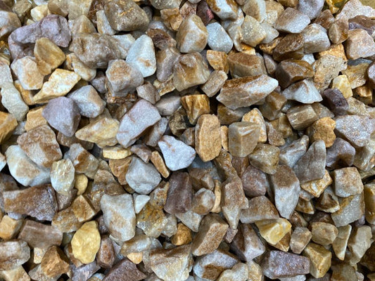 A close-up of a pile of irregularly shaped, mixed-color 20mm Spey Chippings from Brisks in shades of brown, tan, and gray. Ideal as a bulk bag landscaping aggregate for creating a natural, rugged surface pattern.