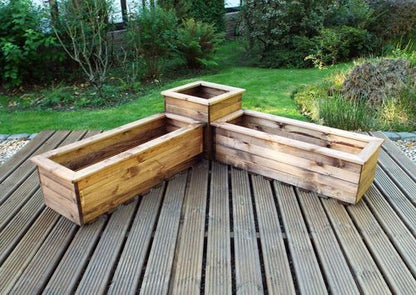 Elegantly placed on the wooden deck, the Charles Taylor Trading Corner Planter Set features an L-shaped English design. The sustainably sourced wood is beautifully showcased in its charming emptiness, with vibrant green grass and shrubs completing the harmonious backdrop.