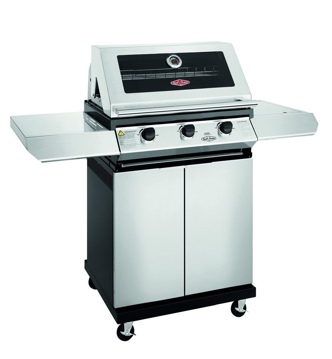 A stainless steel Brisks BeefEater 1200S Series 3 Burner BBQ & Trolley, featuring a built-in thermometer, two control knobs on the front panel, and two side shelves. Perfect for outdoor cooking, this grill is mounted on a wheeled cart with a storage compartment below.