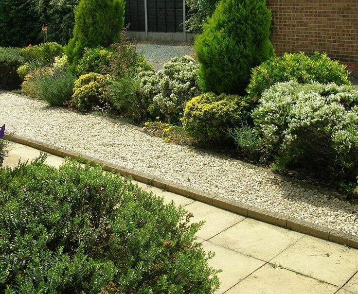 a garden with a gravel path between two buildings