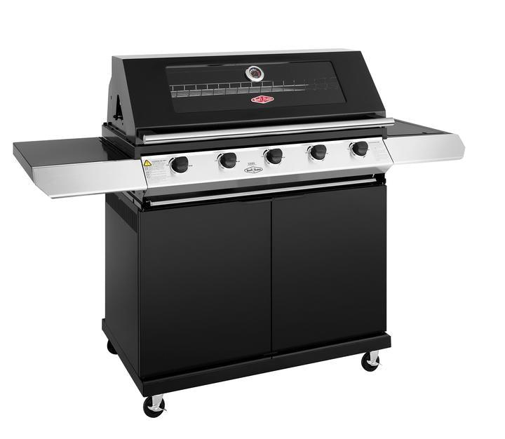 A sleek, modern black gas grill with stainless steel accents. Part of the Brisks BeefEater 1200E Series 5 Burner BBQ & Trolley, it features five burners with control knobs, foldable side shelves, a temperature gauge, and a large enclosed storage compartment below. The grill is mounted on four caster wheels for easy mobility. Perfect for elevating your outdoor living experience.