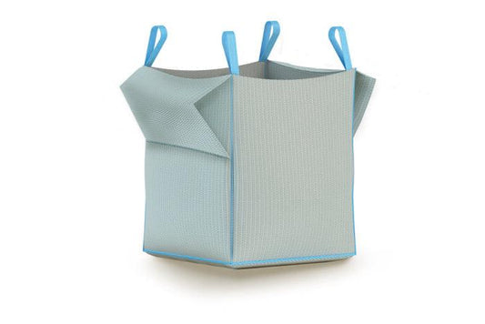 A large, light gray Brisks Empty Bulk Bag with blue trim and four blue handles, one on each top corner, stands upright. The fabric has a textured pattern, reminiscent of durable woven polypropylene bags, and the bag's sides are slightly folded outward, suggesting room for expansion.