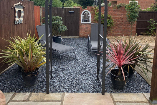 a patio area with chairs and plants in it