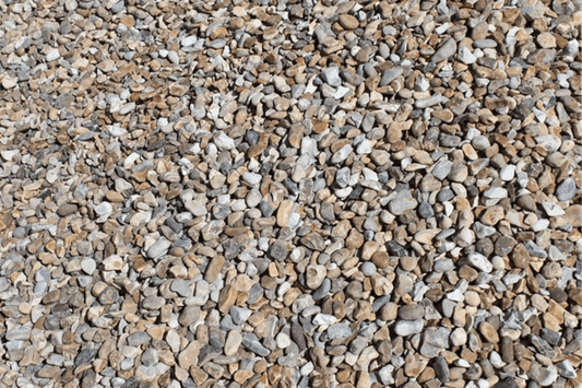 A close-up view of a large pile of small, irregularly shaped pebbles and stones in varying shades of beige, gray, and white. This Brisks 10-20mm Shingle Gravel boasts a rough texture with stones closely packed together, filling the entire frame—perfect for landscaping or drainage projects.