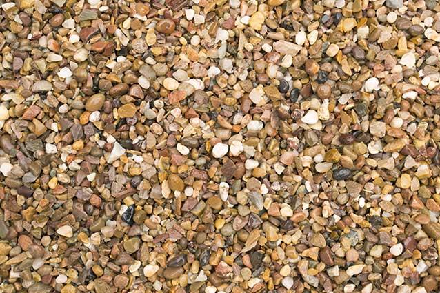 A close-up view of a collection of small, variously colored pebbles and Brisks 04-10mm Pea Gravel. The pebbles range in shades of brown, tan, white, and black, with some appearing more rounded and others more jagged, creating a textured mosaic-like appearance perfect for landscaping.