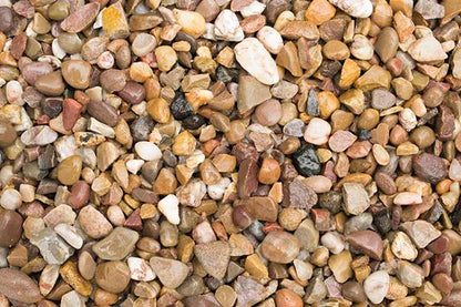 A close-up view of a collection of small, multicolored pebbles and stones used for landscaping. The Brisks 10-20mm Shingle Gravel varies in shape, size, and color, including shades of brown, tan, white, black, and gray, creating a diverse and textured pattern ideal for effective drainage.