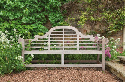 a wooden bench in a garden surrounded by flowers
