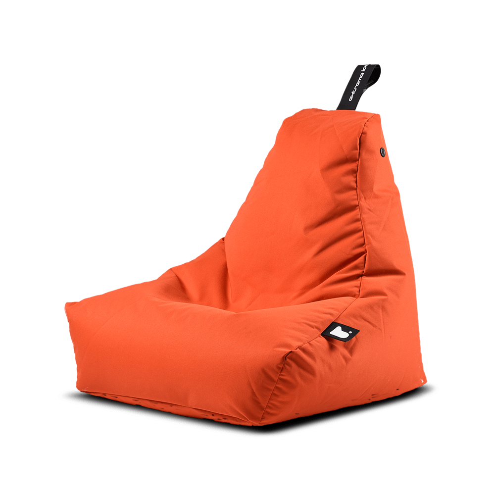 An orange Extreme Lounging Outdoor Mini B-Bag by Brisks with a triangular backrest, perfect for extreme lounging. The premium quality fabric appears smooth and durable, featuring a small black tag with a white logo on the side. For easy transportation, there's also a black carry handle on top.