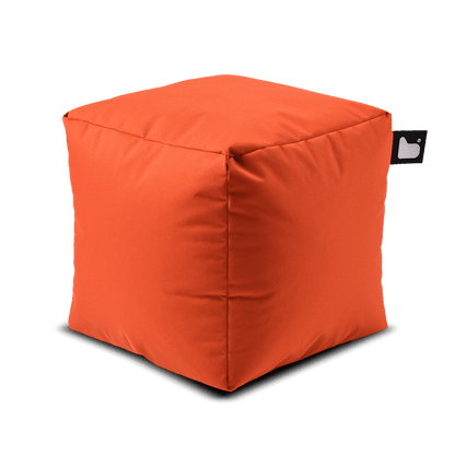 A bright orange, cube-shaped Brisks Extreme Lounging Outdoor B-Box with a small black tag on one corner. Filled with polystyrene beads, the fabric appears soft and slightly textured. The Extreme Lounging Outdoor B-Box stands out against the plain background, showcasing its simple, modern design perfect for a garden retreat.