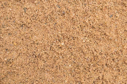 Close-up image of loose, fine Brisks 0-4mm Sharp Sand with a few small pebbles and granules visible. The surface appears dry and granular, showcasing a mixture of light and dark brown particles—perfect for landscaping or block paving projects.