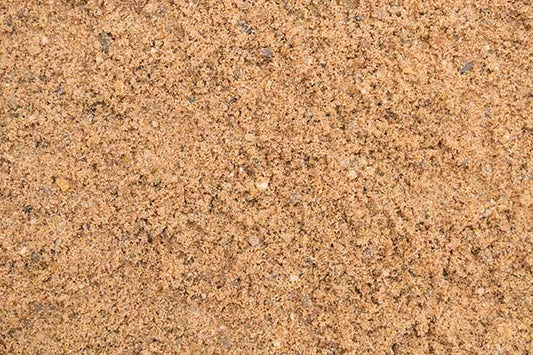 Close-up image of loose, fine Brisks 0-4mm Sharp Sand with a few small pebbles and granules visible. The surface appears dry and granular, showcasing a mixture of light and dark brown particles—perfect for landscaping or block paving projects.