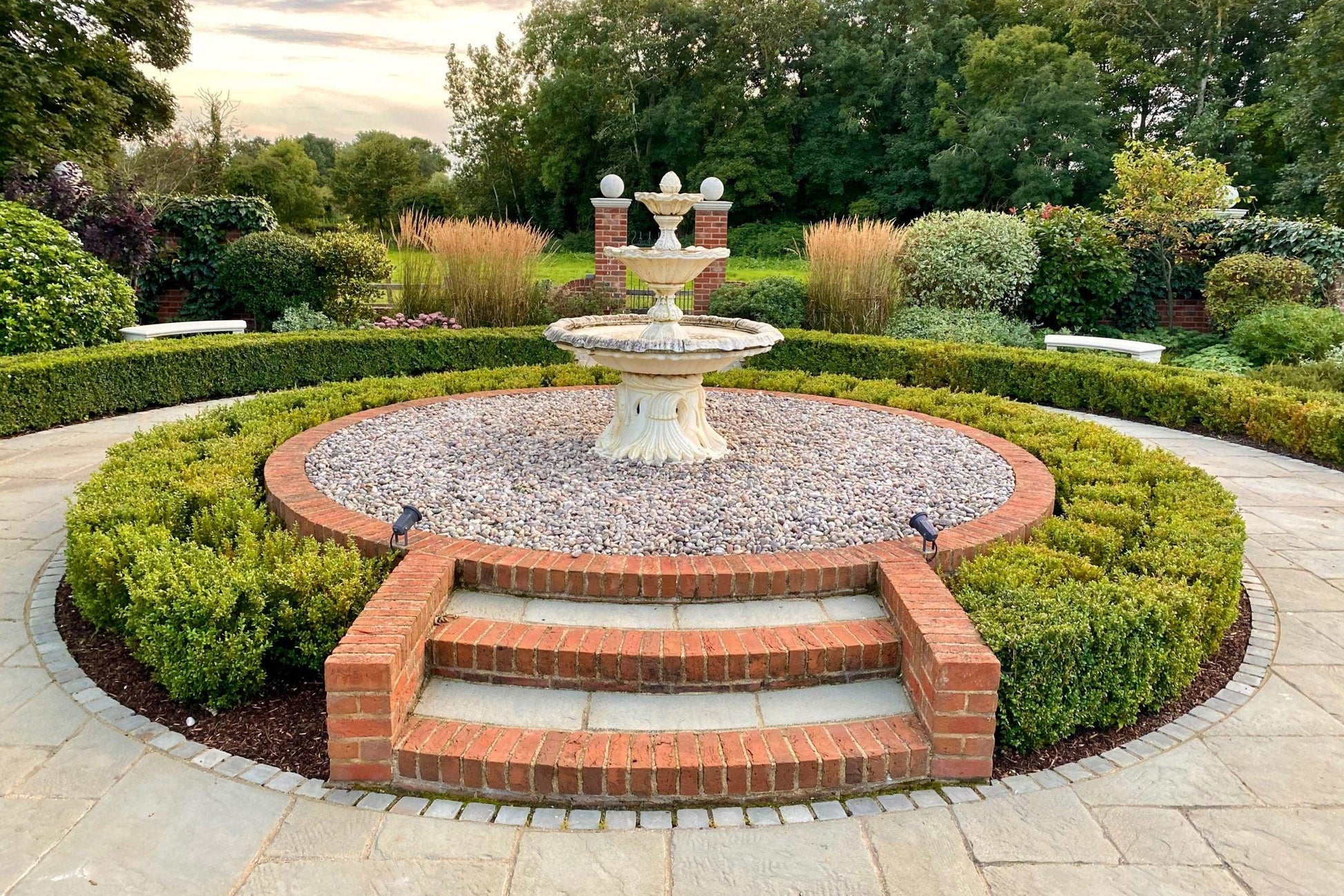 a garden with a fountain surrounded by hedges