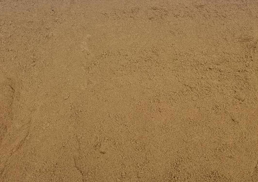 A close-up image of a textured, sandy surface with small pebbles and grains of sand. The color is a consistent light brown, similar to Brisks 0-2mm Yellow Building Sand, highlighting the rough, granular nature. Ideal for construction applications, the surface appears dry and natural.